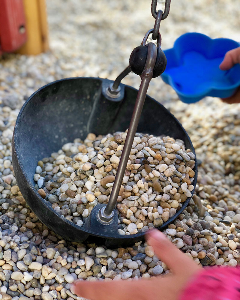 Nahaufnahme einer großen Schaufel mit Flaschenzug zum Spielen mit Sand und Steinen.